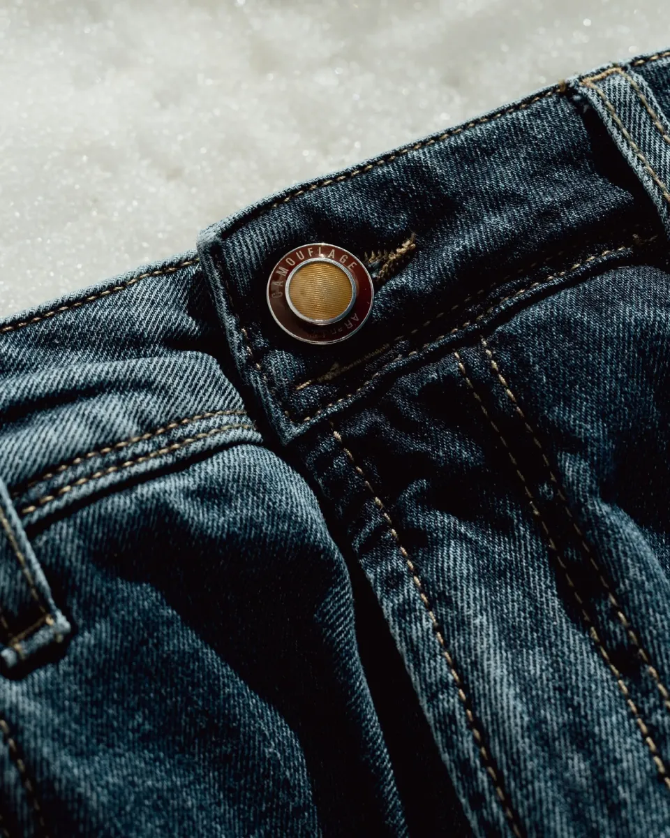 Close-up of Camouflage premium denim button and waistband construction