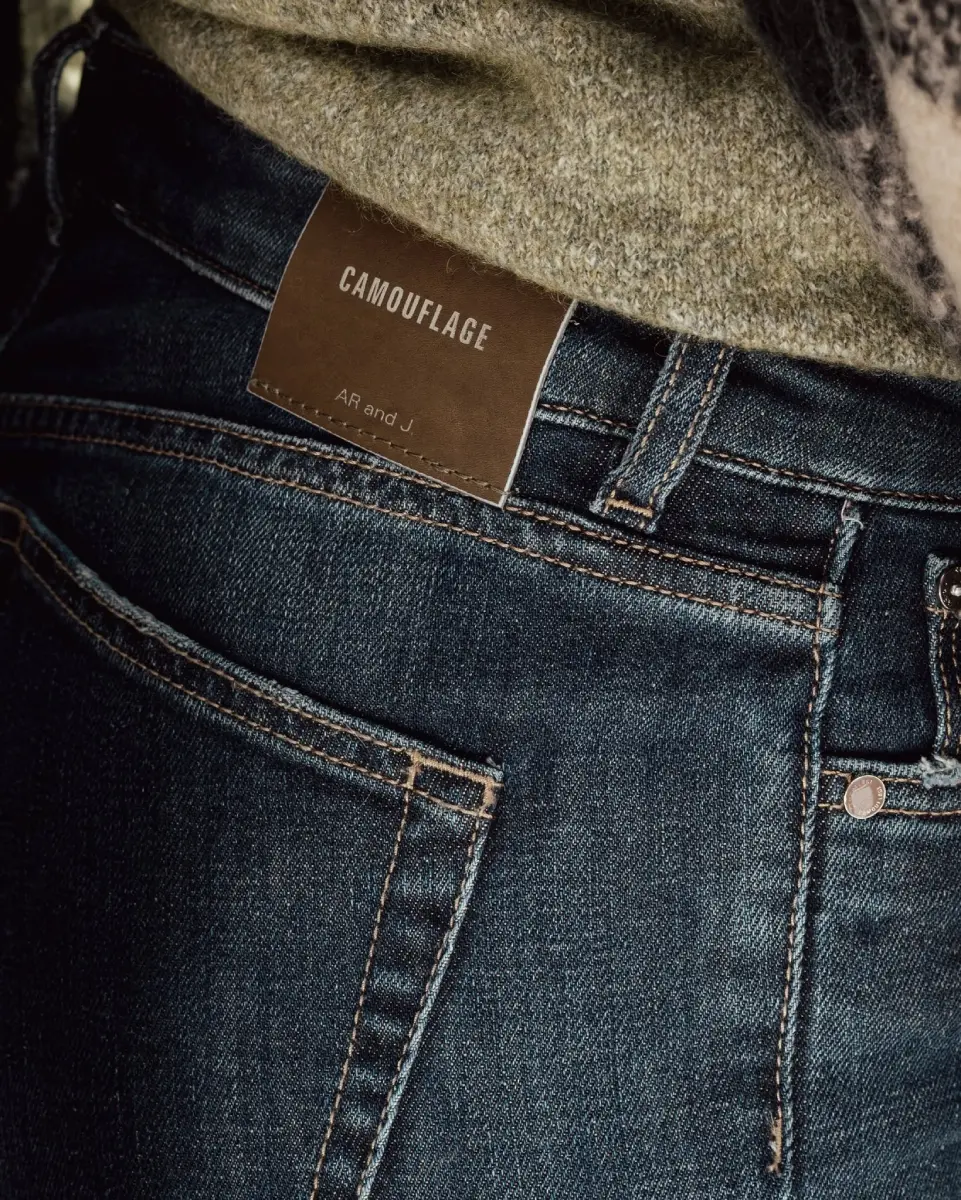 Close-up of Camouflage dark wash denim jeans with leather waistband patch