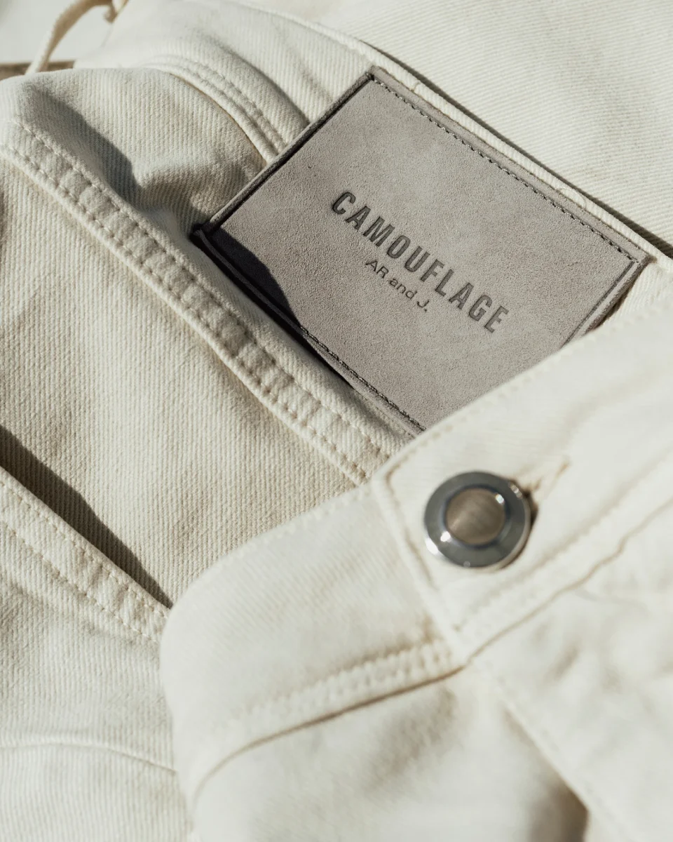 Close-up of Camouflage light wash denim featuring branded waistband detail