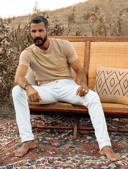 Man sitting on a bench in white jeans by Camouflage AR and J