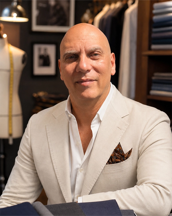 Headshot of John Greco posing in a light suit jacket.